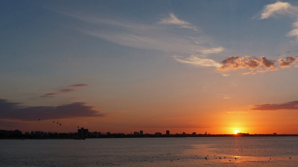 Sonnenaufgang mit daneben fliegenden Heißluftballons