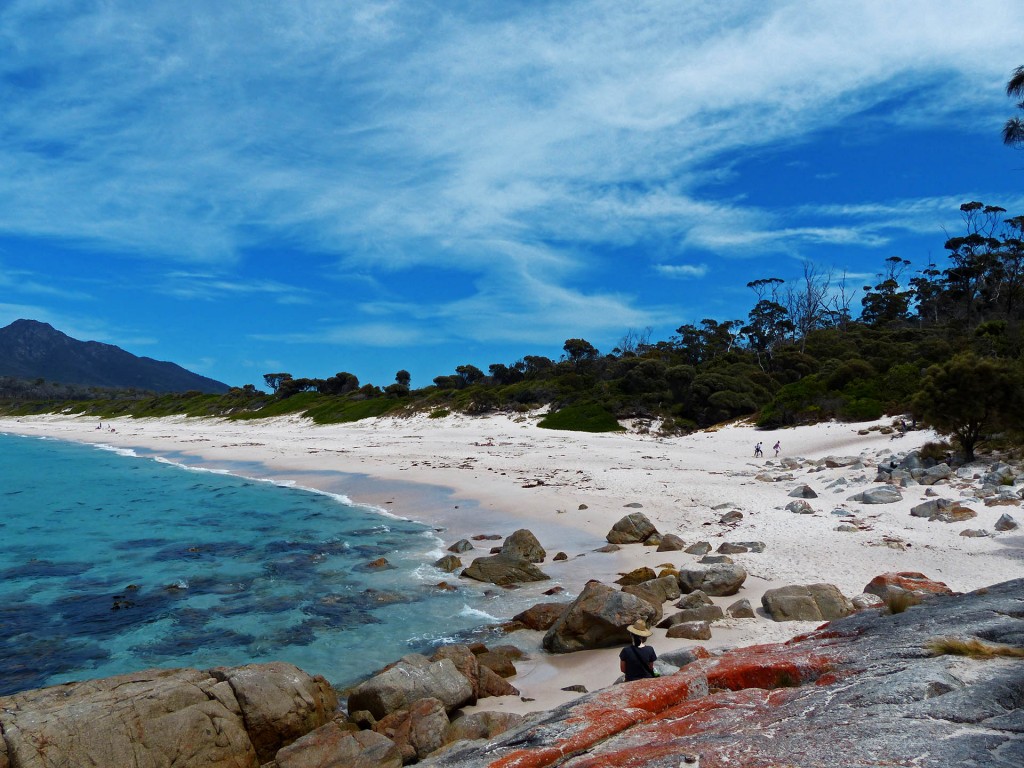Alina sitzend auf den roten Steinen vor dem Strand an der Wineglass Bay